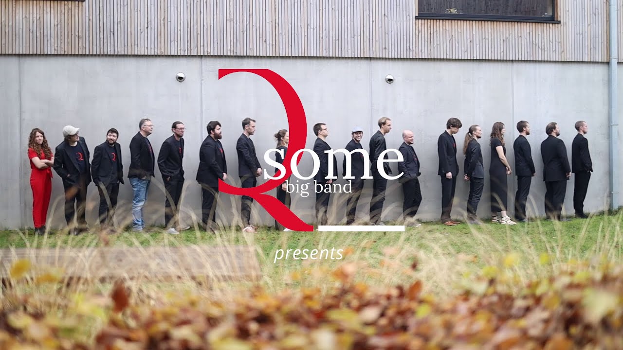 The musicians of Q-Some Big Band lined up against a wall, with the band logo